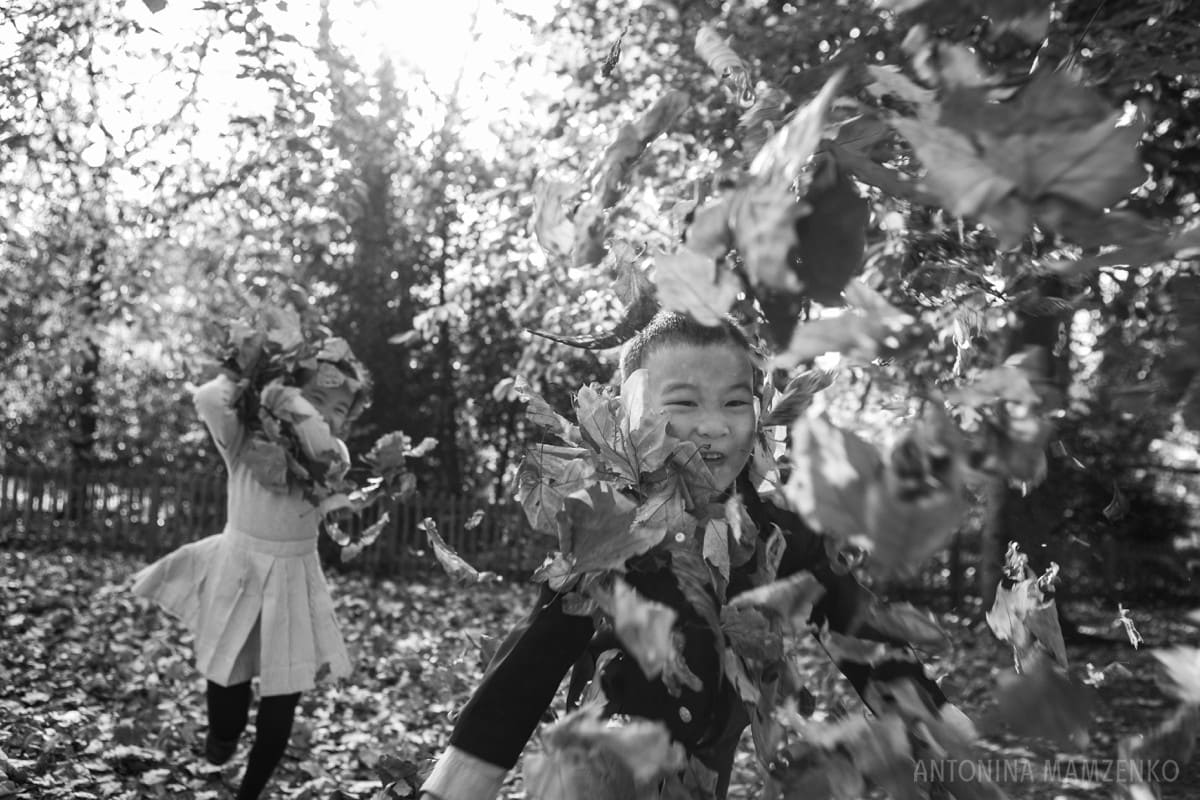 children throwing leaves at a photographer during a photoshoot in holland park
