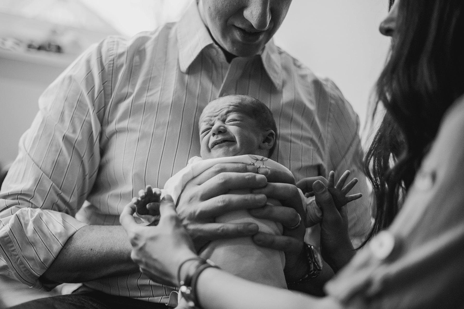 photo of a dad holding a crying newborn baby