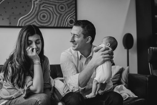 parents holding a newborn baby laughing